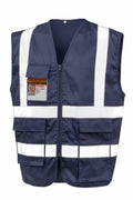 Product R477X from Result Safeguard is a navy blue safety vest featuring reflective white stripes and multiple pockets. It includes a clear ID pocket on the upper left side holding an ID card, and is zipped up for neat display against a plain background.