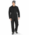 A person is wearing a black Result R510X coverall, grey beanie, and black shoes. They are standing and looking slightly to the side.