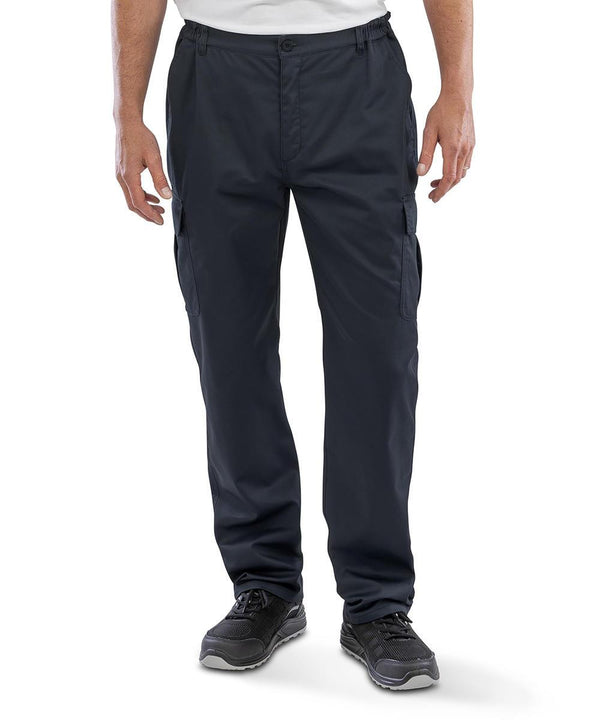 A person is shown from the waist down, standing against a plain white background, wearing Result Recycled Recycled work-guard utility trousers with a white shirt and black trainers.