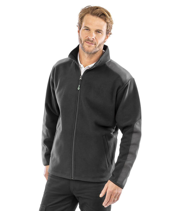 A man with short light brown hair and a beard wears the Result Workguard Work-Guard recycled heavy duty microfleece jacket in black over a white shirt. He stands against a plain white background, looking at the camera with a neutral expression.