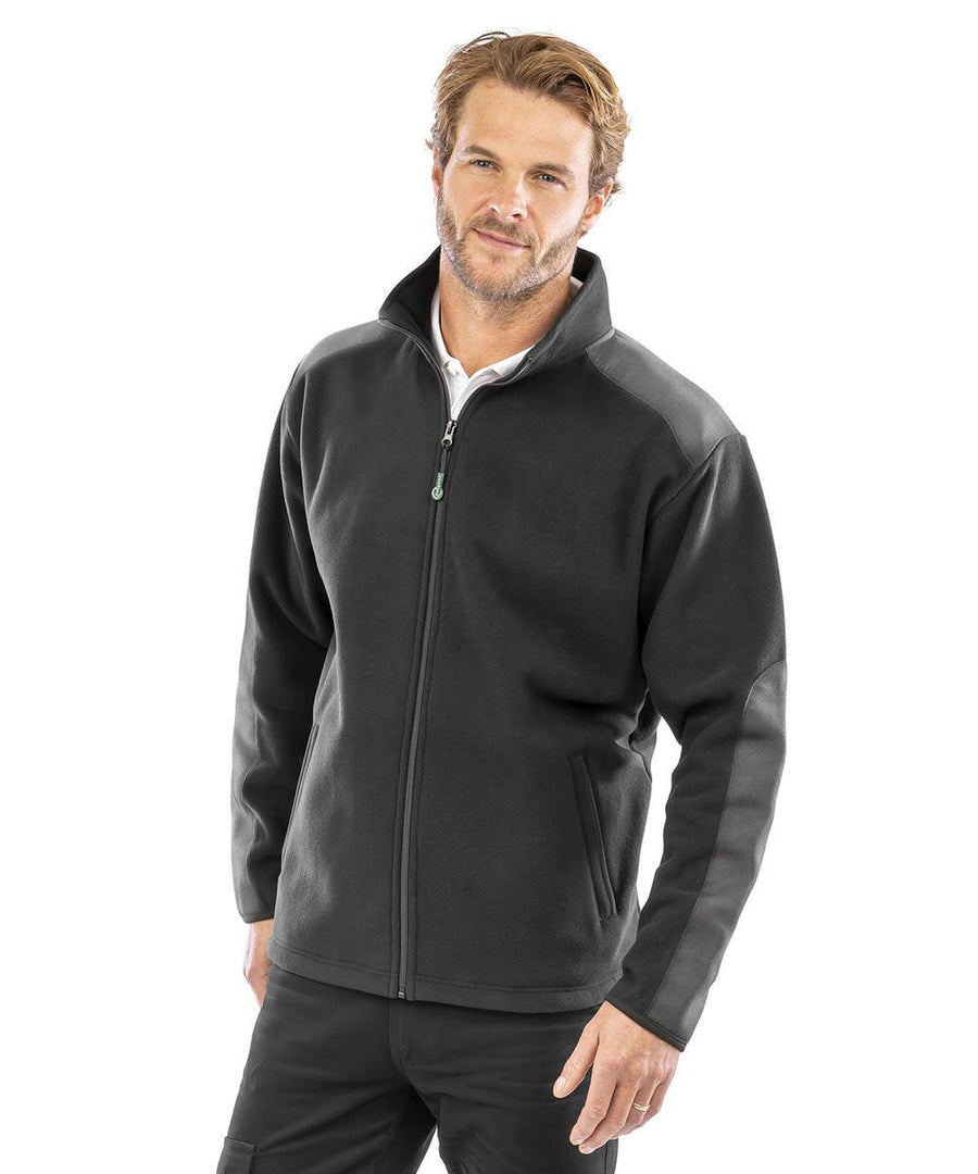 A man with short light brown hair and a beard wears the Result Workguard Work-Guard recycled heavy duty microfleece jacket in black over a white shirt. He stands against a plain white background, looking at the camera with a neutral expression.