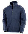 The Fleece is a navy blue jacket featuring a full front zip, stand-up collar, dark blue shoulder and sleeve patches, two side pockets, and a straight hem.