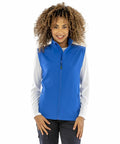 A person with curly hair is wearing a bright blue Result R902F zip-up vest over a white long-sleeve shirt.