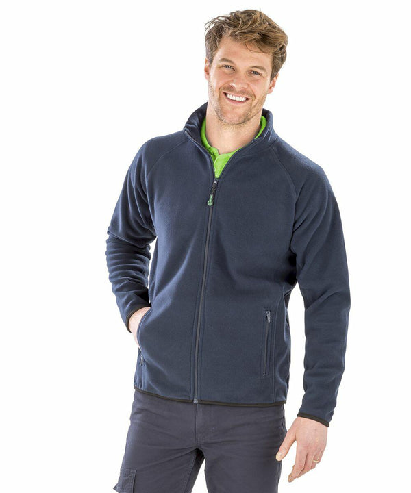 A man wearing a dark blue Result R903X and green shirt smiles at the camera with one hand in his pocket.