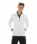 A man with sunglasses on his head smiles while wearing a white Result R907X zip-up jacket with both hands in the pockets.