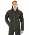 A man stands facing forward wearing a Result Genuine Recycled R911M zip-up jacket with his left hand in his pocket.