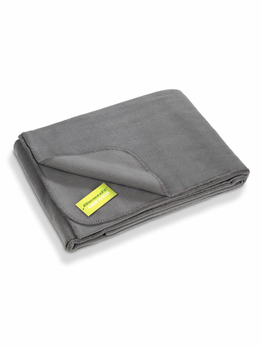 A neatly folded blanket in a gray hue with a small green label at one corner, set against a plain white backdrop, from the Result Genuine Recycled collection, model R939X.