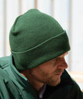 A person wearing a dark green Result RC029 and a matching green jacket looks down.