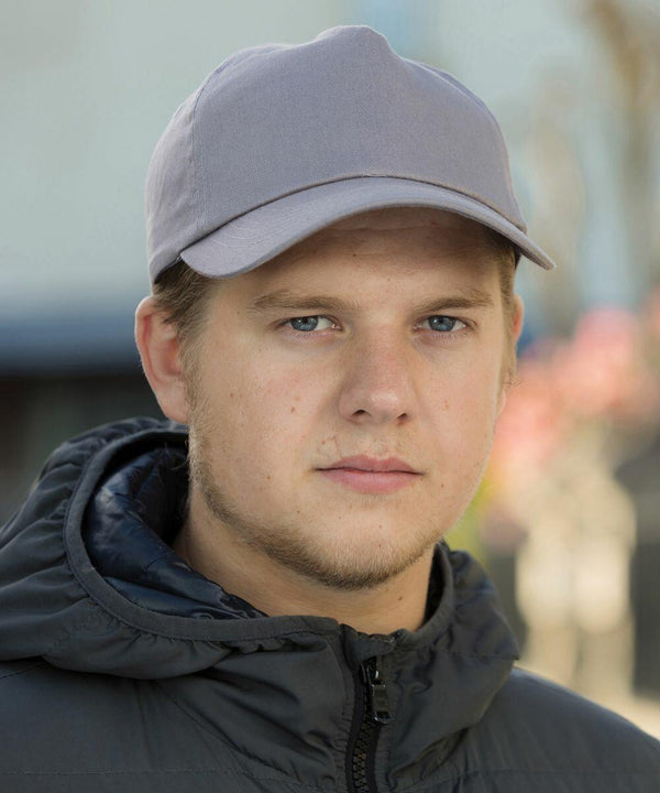 A man with short hair wears a gray Result RC05X cap and a dark jacket, looking straight at the camera with a neutral expression. The background is slightly blurred.