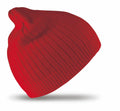 A red knit beanie from the Result Winter Essentials, model RC074, is showcased against a white backdrop. The beanie is slightly tilted, highlighting its ribbed texture and stretchy material.