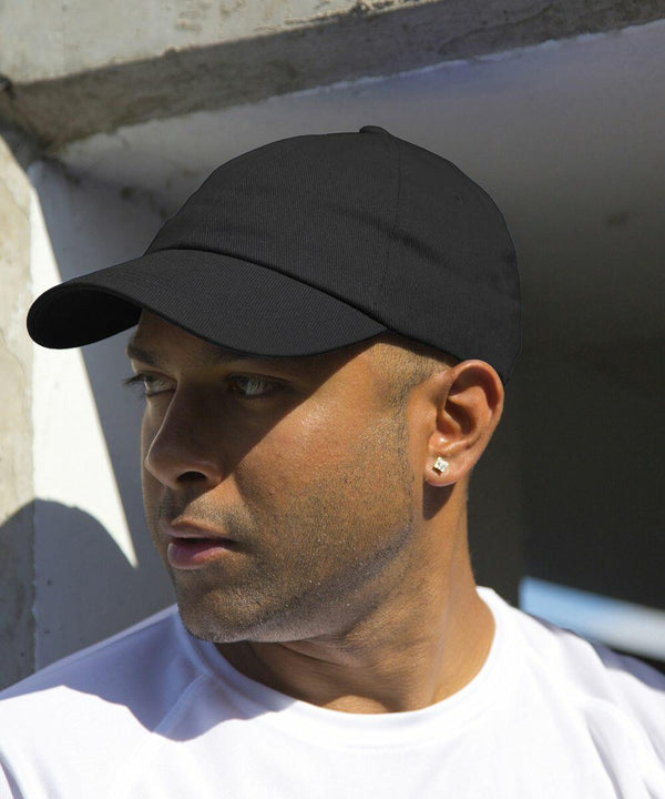 A person wearing a black cap and white shirt looks to the side while standing outdoors in the Result RC10X.