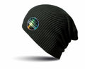 A dark green ribbed beanie from Result Winter Essentials featuring a circular patch labeled "RC31X Deluxe Quality" on the side.
