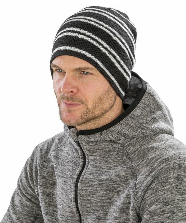 A man wearing a gray Result RC354 hoodie and a black and white striped beanie is looking to the side.