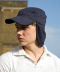 Person wearing a navy blue Result RC76X with ear flaps, looking to the side, dressed in a white polo shirt.