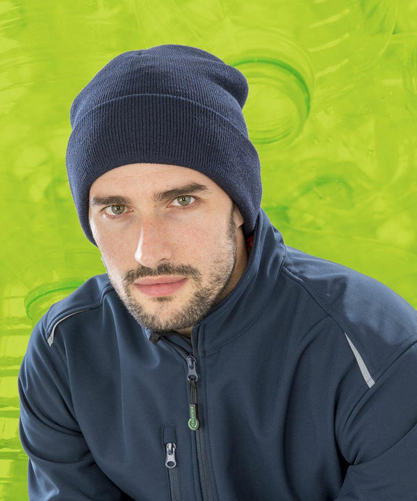 Man wearing a navy **Result RC933** beanie and blue jacket against a green background with circular patterns.