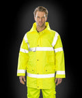 A person is wearing a Result RE18A high-visibility yellow jacket with reflective strips. The background is black.