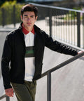 A man in a Regatta RG089 jacket and green pants stands near a railing outdoors, looking into the distance.