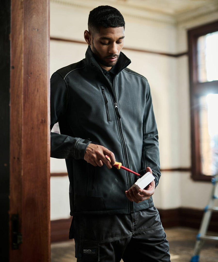Man in a black jacket using a Regatta RG158 on a wall socket indoors.