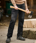 Person holding an RG235 from Regatta next to chopped wooden logs, wearing black pants and dusty boots, in an outdoor setting.