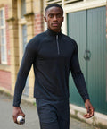 A man in a black athletic outfit walks outside holding a silver RG365 water bottle by Regatta, with buildings in the background.
