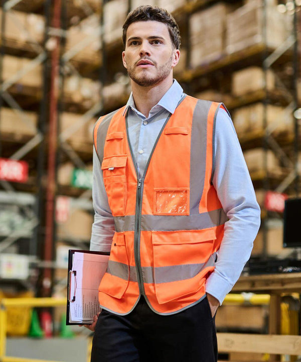 A person wearing an orange safety vest holds a Regatta RG469 clipboard while standing in a warehouse.