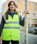 A person in a fluorescent safety vest holds a Regatta RG470 on a city street.