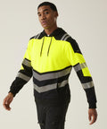 A man wears the Regatta High Visibility Hi-Vis X-Pro Hoodie (Class 2) in black and neon yellow with reflective grey stripes, standing against a plain background and facing slightly left with one arm extended.