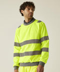 A man wears the Regatta High Visibility Hi-vis Pro contrast crew neck sweatshirt, neon yellow with reflective grey stripes, standing against a plain light background.