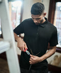 A man in a black polo shirt uses Regatta RG524 wire cutters to work on electrical wiring next to a white ladder.