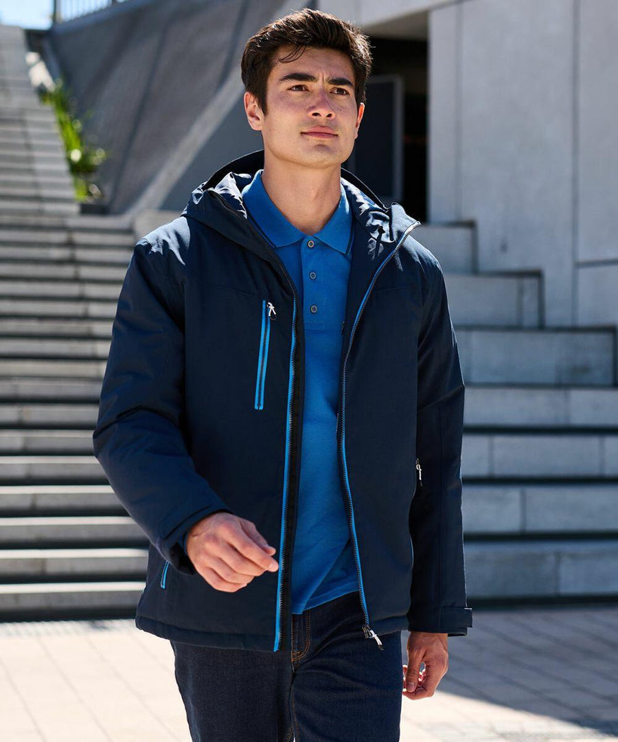 A man wearing a dark blue Regatta RG580 and light blue shirt walks outside near a set of stairs.