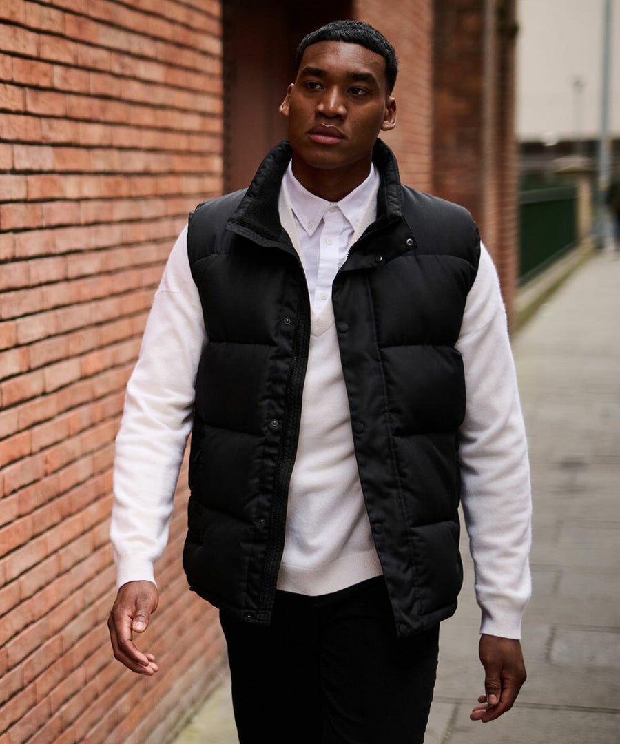 A person in a white shirt and black Regatta RG586 is walking along a brick wall in an outdoor setting.