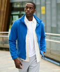 A man wearing a blue Regatta RG601 over a white shirt stands outdoors near a modern building.