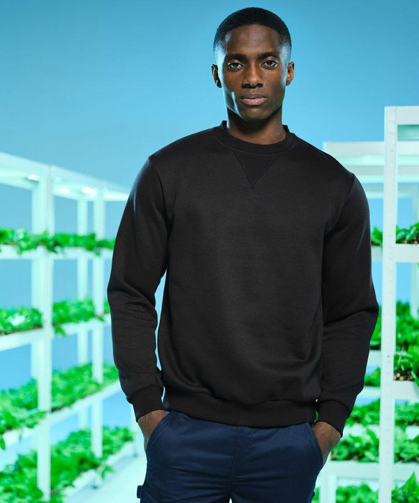 A person in a black sweatshirt stands indoors, with vertical indoor farming racks filled with green plants in the background. They're working with the RG614 from Regatta.