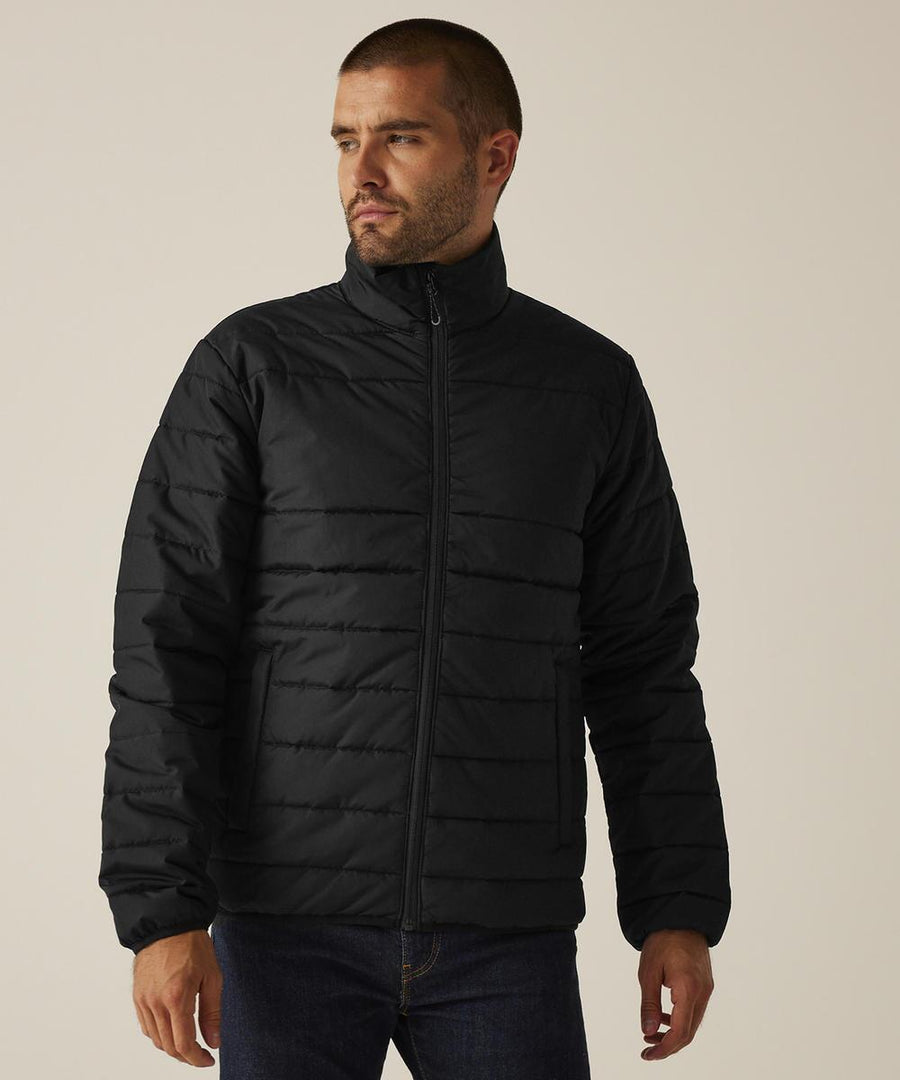 A person wearing the Regatta Professional Essential thermal jacket in black and dark jeans stands against a plain, light background, gazing off to the side.