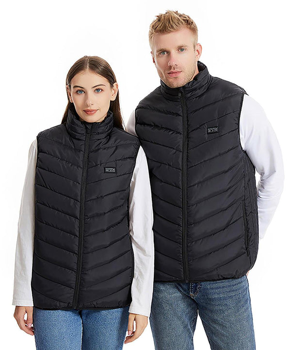 A woman and a man stand side by side against a plain white background, both wearing matching Ribbon Eskimo unisex heated padded bodywarmers over white long-sleeve shirts and blue jeans.