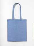 A blue fabric tote bag, known as the RL600 from Nutshell, with two handles is laid flat against a white background. The bag features a simple, plain design without any visible patterns or logos.