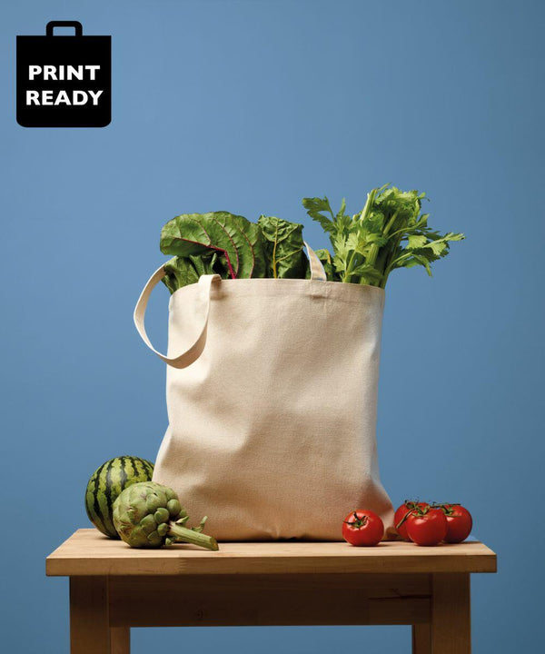 Nutshell RL650 filled with leafy greens placed on a wooden table with a small watermelon, three tomatoes, artichoke, and bell pepper against a blue background.