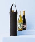 Three wine bottles are shown on light blue steps. One is inside a Nutshell Recycled Premium Canvas Bottle Bag, while the other two—one with a white label and one with a dark label—stand next to each other.