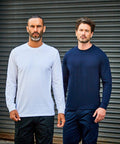 Two men with beards stand side-by-side in front of a metal roller door; one wears a white long-sleeve RX152 shirt and black pants, the other wears a navy long-sleeve RX152 shirt and matching pants by ProRTX.