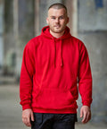 A man with a short haircut wearing a red ProRTX RX350 hoodie and black pants poses for a photo in an urban setting.