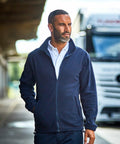 A man with short hair and a beard is wearing a navy blue ProRTX RX402 over a white shirt, walking outdoors with a truck in the background.