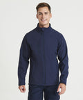 A person is standing and smiling, wearing a navy blue ProRTX RX530 zip-up jacket and matching pants with pockets. The background is plain white.