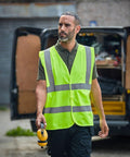 A person wearing a high-visibility vest holds a ProRTX RX700 in hand while standing in front of a van with its back doors open.