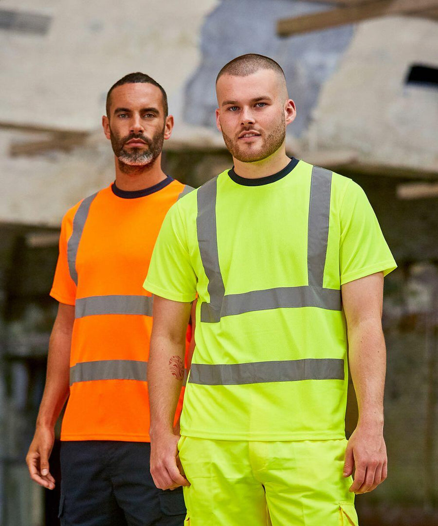 Two men stand side by side, wearing high-visibility shirts: one in orange with reflective stripes and the other in neon yellow with reflective stripes. Both are sporting the RX720 from ProRTX. A blurry industrial background is visible.
