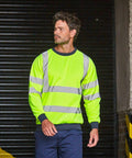 A man wearing a high-visibility yellow ProRTX RX730 safety sweatshirt with reflective stripes stands in front of a dark industrial background.
