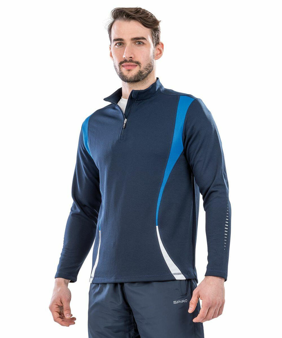 A man stands wearing a dark blue long-sleeve athletic top with blue and white accents, featuring a quarter-zip front. He also wears matching blue athletic pants, both part of the Spiro S178X collection.