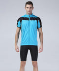 A man stands wearing a blue and black Spiro S188M cycling jersey with black cycling shorts against a plain gray background.
