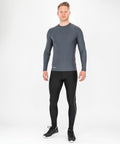 A person stands against a white background wearing a Spiro S251M long-sleeve gray athletic shirt, black athletic leggings, and black sneakers.