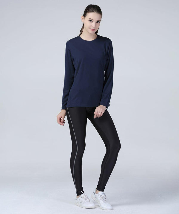 A woman stands against a plain background wearing a navy long-sleeve shirt, black leggings, and white Spiro S254F sneakers. She is looking at the camera while slightly leaning on one leg.