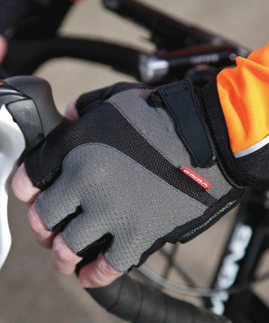 A person wearing Spiro S257X gray and black cycling gloves grasps the handlebars of a bicycle.